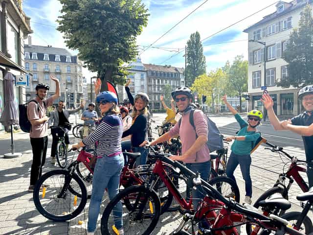 Guests in helmets with red VéloRouge bikes on a Strasbourg street