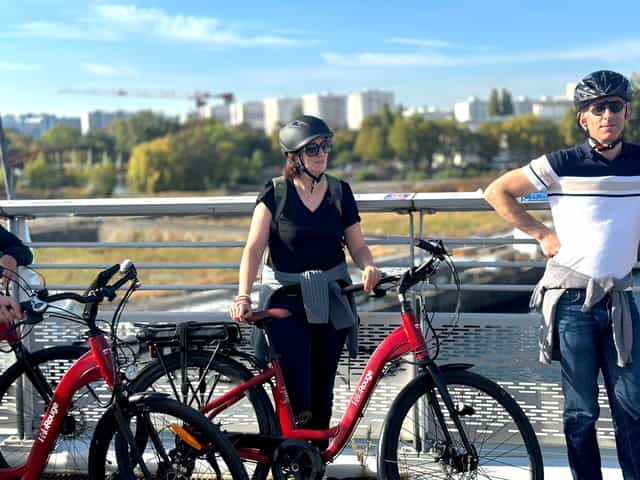Two guests with red VéloRouge bikes by the water